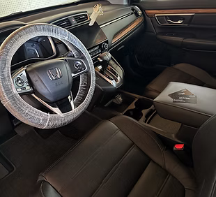 Interior of a Honda vehicle showcasing expertly detailed leather seats, clean dashboard, and steering wheel with protective cover, emphasizing premium mobile detailing service.