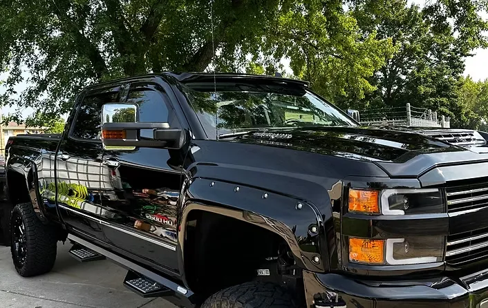 Shiny black lifted 2500 HD pickup truck with custom fender flares and side steps.